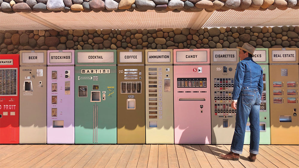 Les détails stylistiques caractéristiques de Wes Anderson jouent dans l'humour du film.  Ici, des distributeurs automatiques bordent l'extérieur du bureau du motel, où des produits de toutes sortes – et pour tous les âges – sont facilement disponibles.