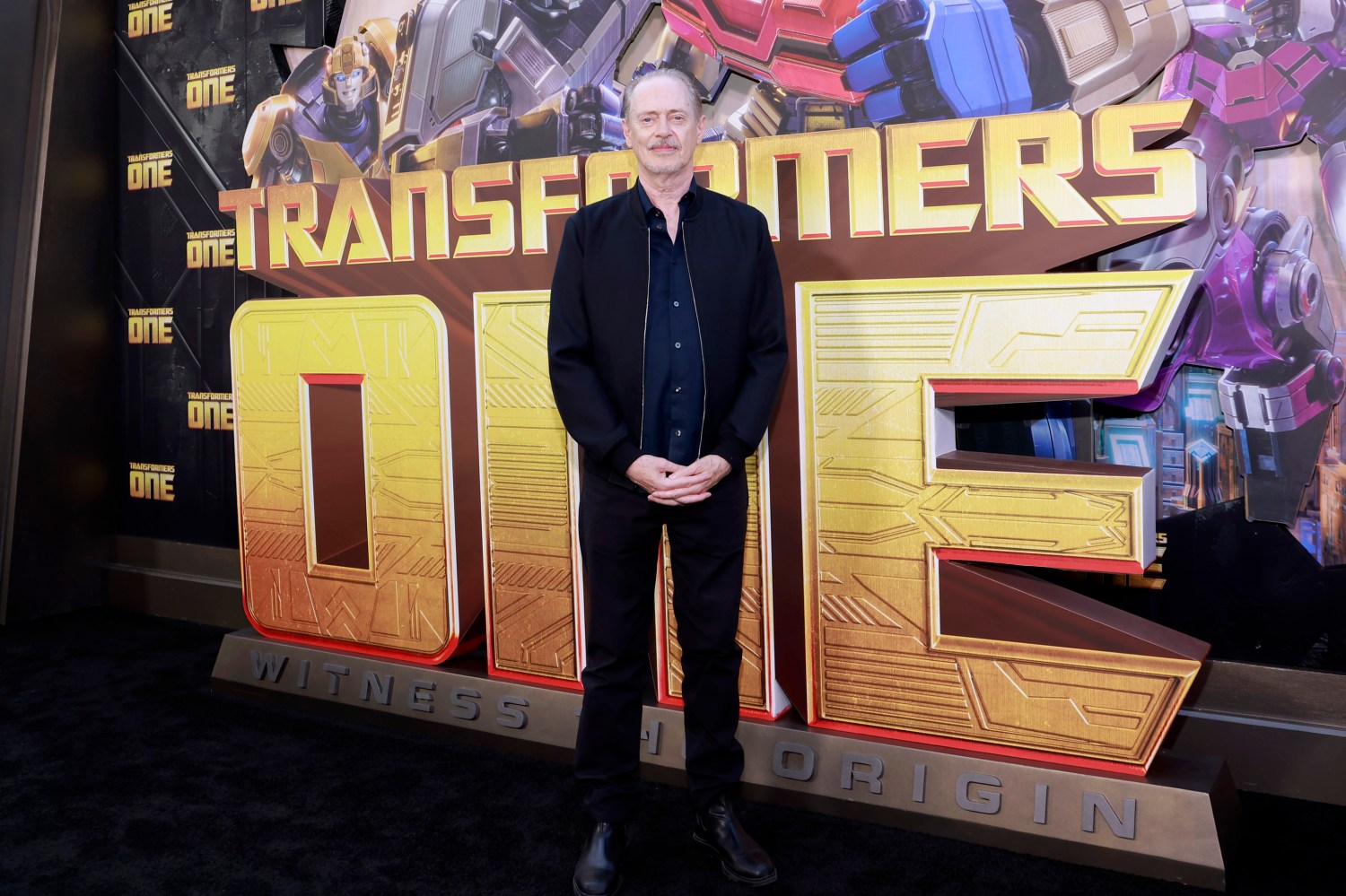 Steve Buscemi pose devant un décor de Transformers One